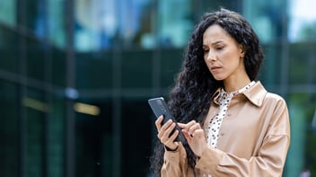 upset woman on smartphone infront of building